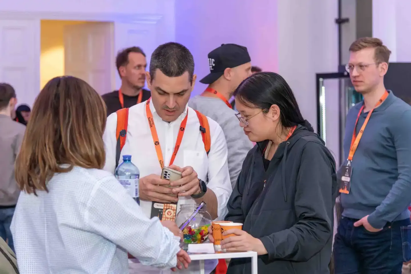 Eventfotograf dokumentiert Netzwerkgespräche beim Sonic Summit in Wien mit mehreren Teilnehmern in casual Business-Kleidung