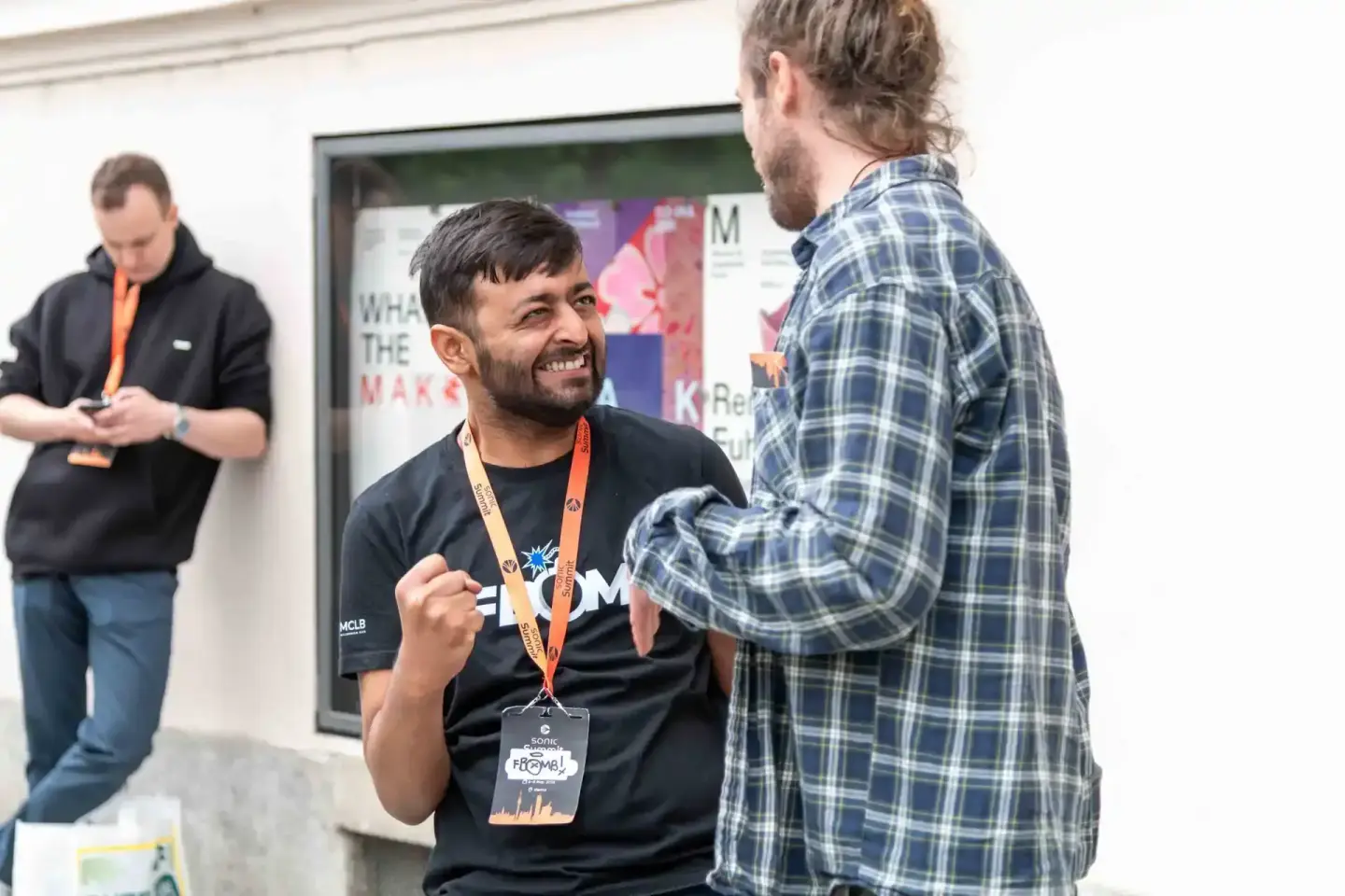 Zwei Männer im Gespräch bei Sonic Summit Event, einer trägt Besucherausweis - Eventfotograf Wien dokumentiert Networking-Mome