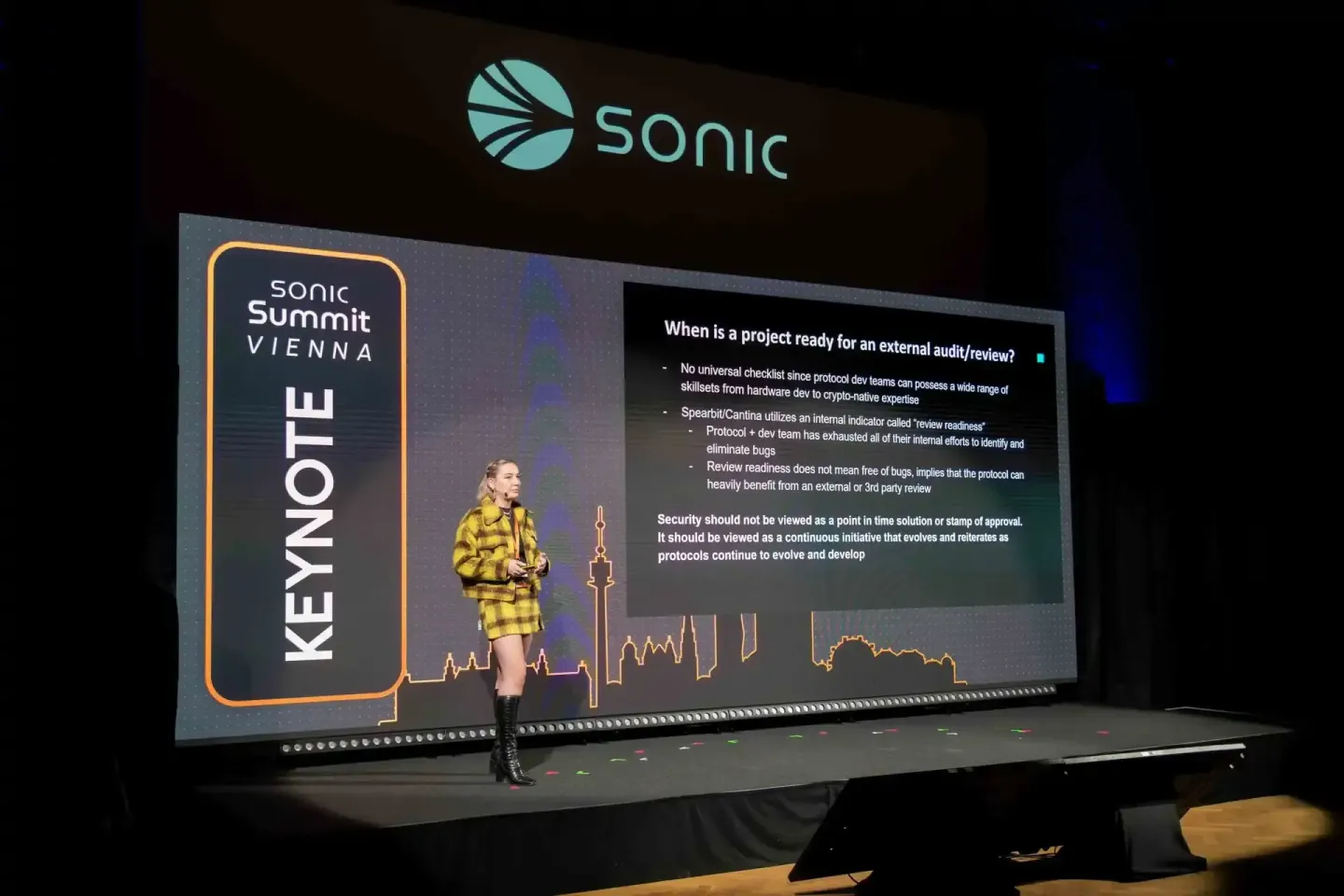 Rednerin im gelben Anzug präsentiert auf der Sonic Summit Vienna 2024 Keynote zu Security Audits und externe Reviews