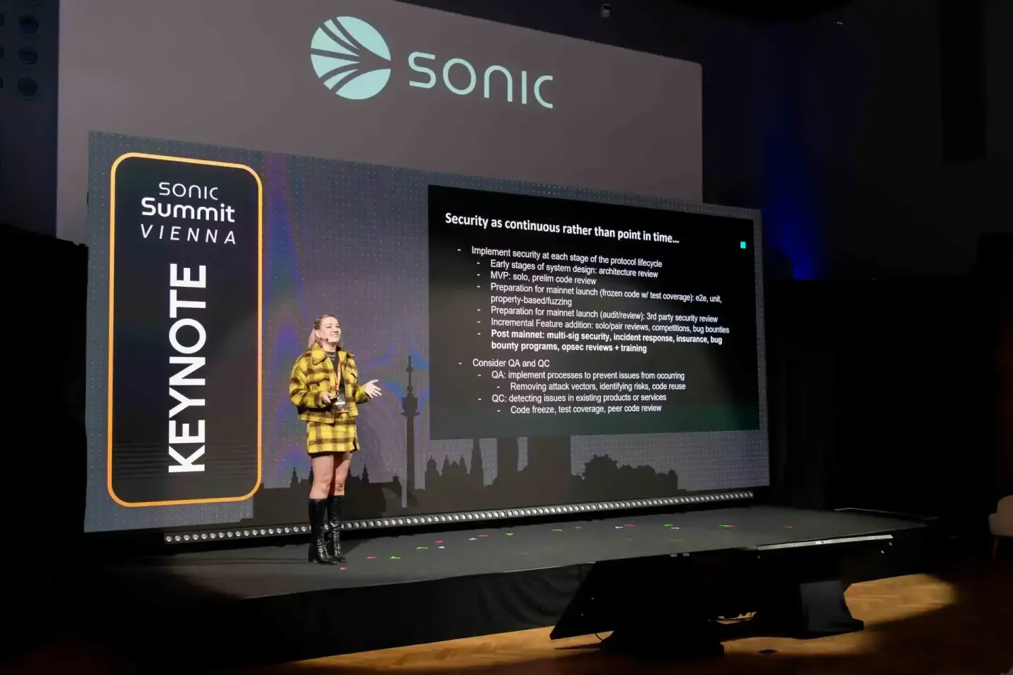 Sprecherin im gelben Blazer präsentiert auf der Sonic Summit Vienna Keynote zu Security Best Practices auf großer Bühne