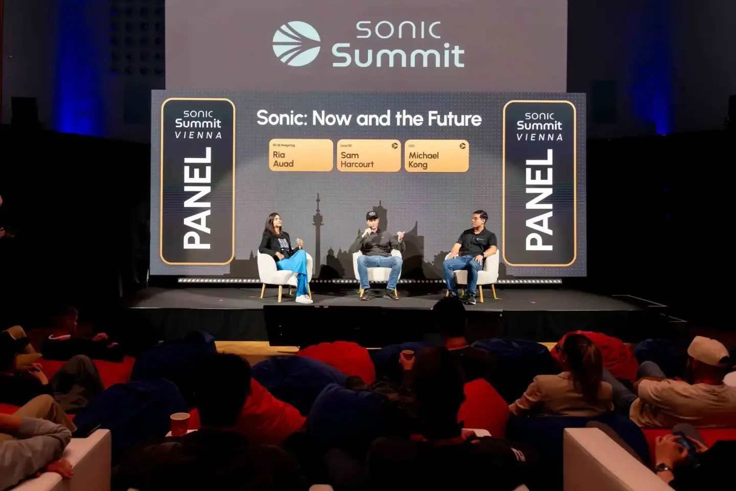 Paneldiskussion beim Sonic Summit Vienna 2024: Drei Sprecher sitzen auf der Bühne vor Publikum, moderiert von Ria Auad, Sam H