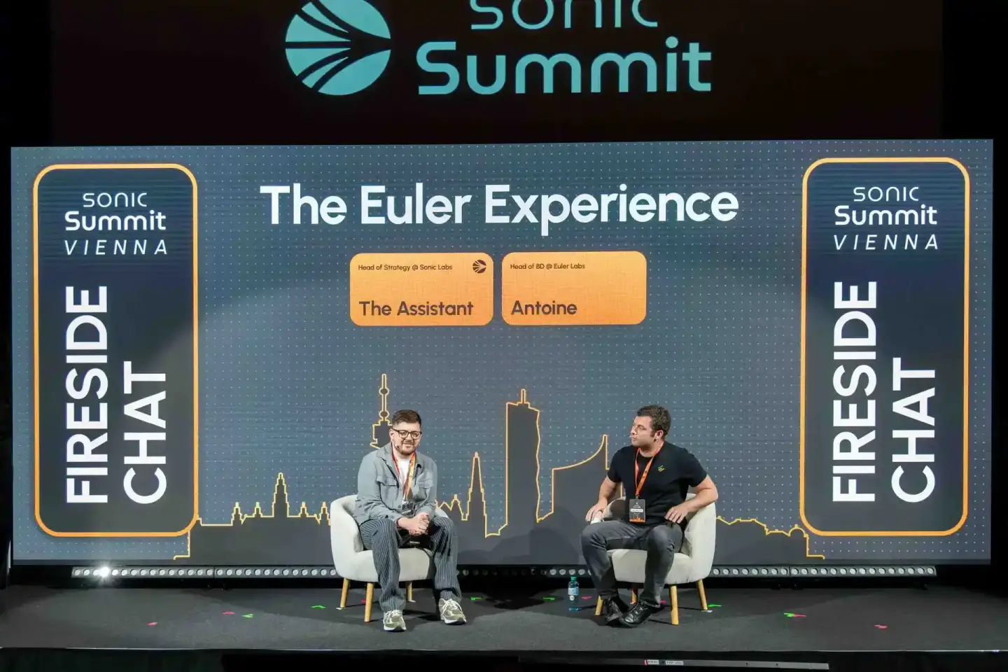Zwei Sprecher sitzen im Fireside Chat bei der Sonic Summit Vienna, im Hintergrund die Skyline Wiens – professionelle Eventfot