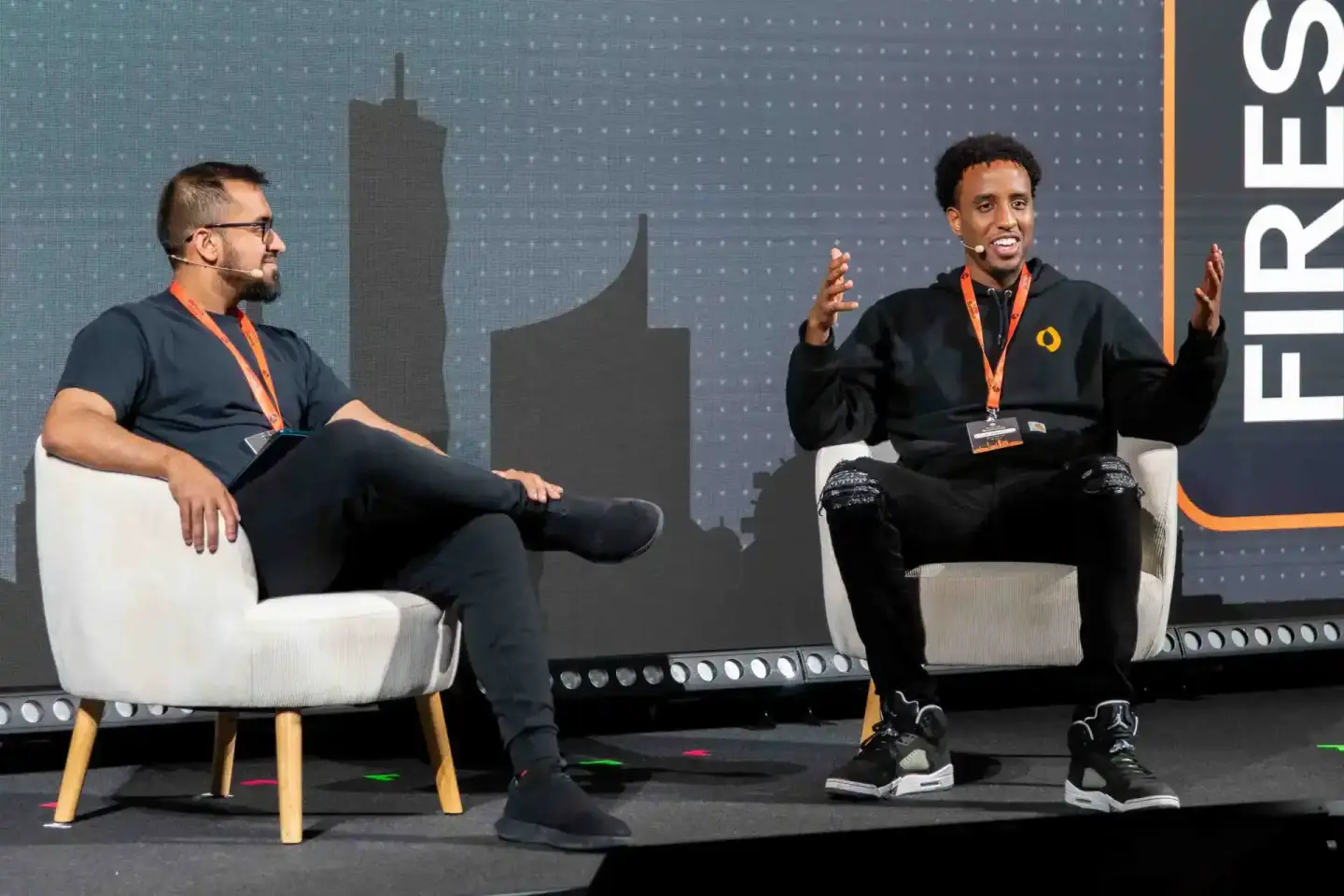 Zwei Sprecher auf der Sonic Summit Konferenz sitzen auf weißen Sesseln und diskutieren auf der Bühne – Eventfotografie Wien