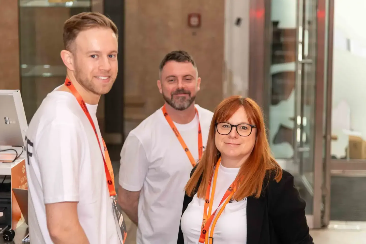 Drei Teilnehmer mit orangenen Lanyards beim Sonic Summit Event – professionelle Eventfotografie Wien
