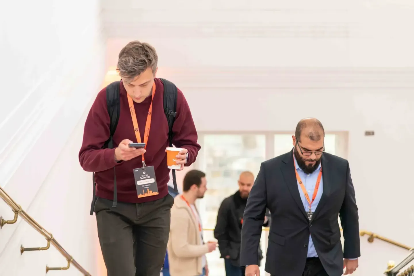 Teilnehmer beim Sonic Summit Event in Wien gehen Treppen hinunter, tragen Akkreditierungen und halten Getränke - Eventfotogra