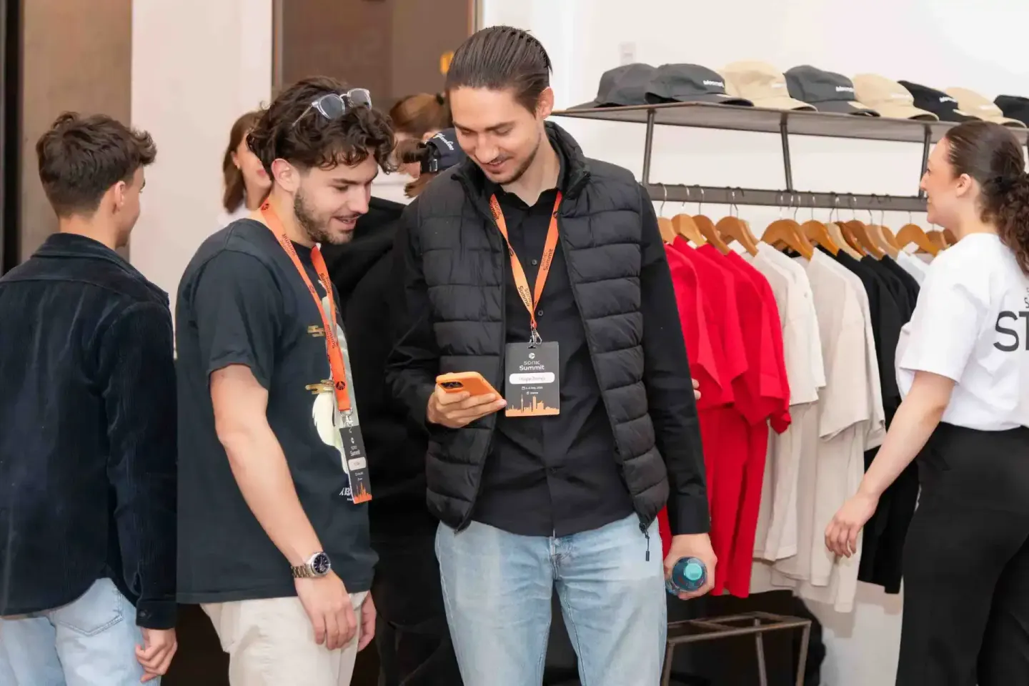 Eventfotograf dokumentiert Networking beim Sonic Summit in Wien mit Besuchern an Kleidungsständer