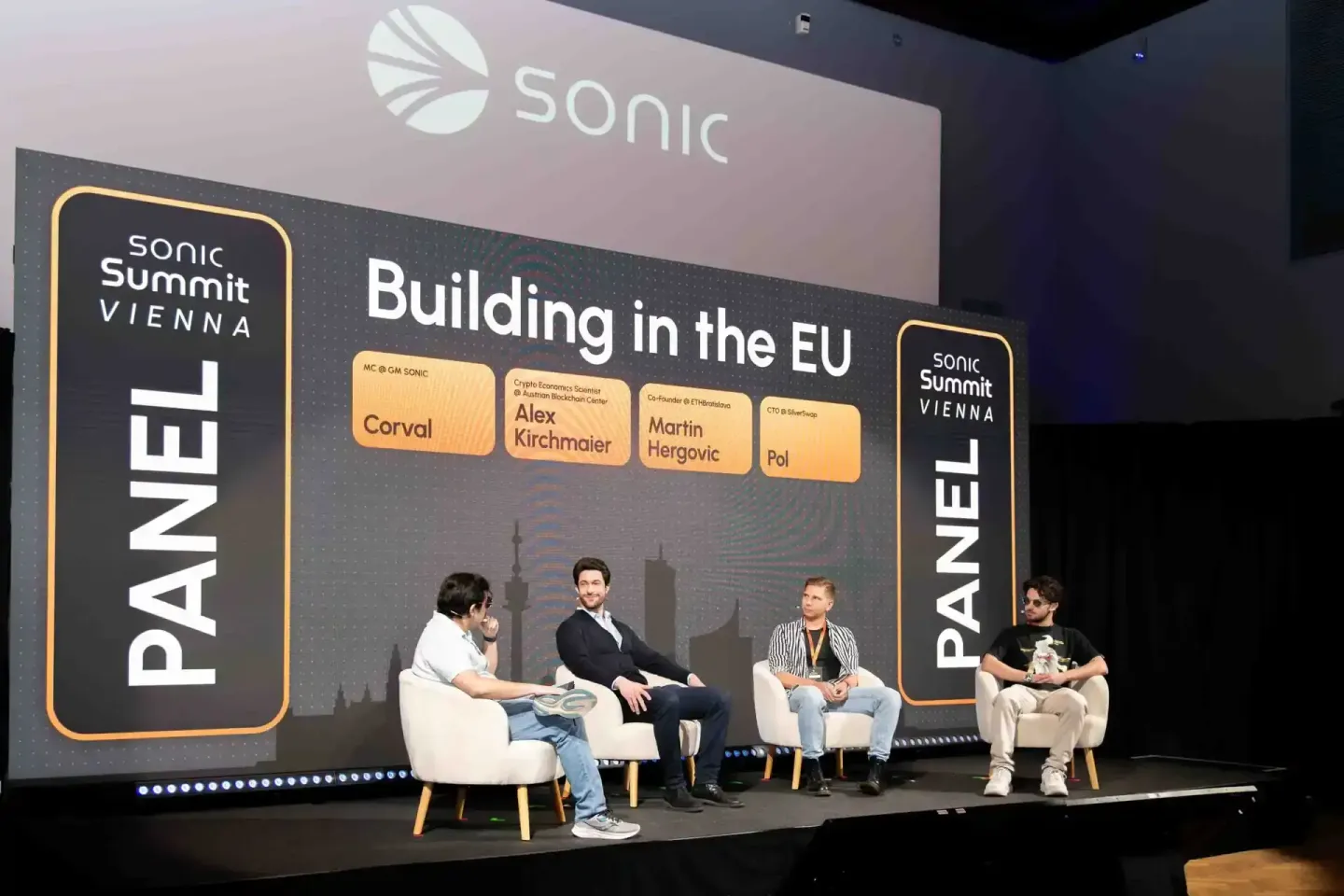 Vier Panelisten auf der Sonic Summit Vienna sitzen in weißen Sesseln auf der Bühne während eines Panels zum Thema Building in
