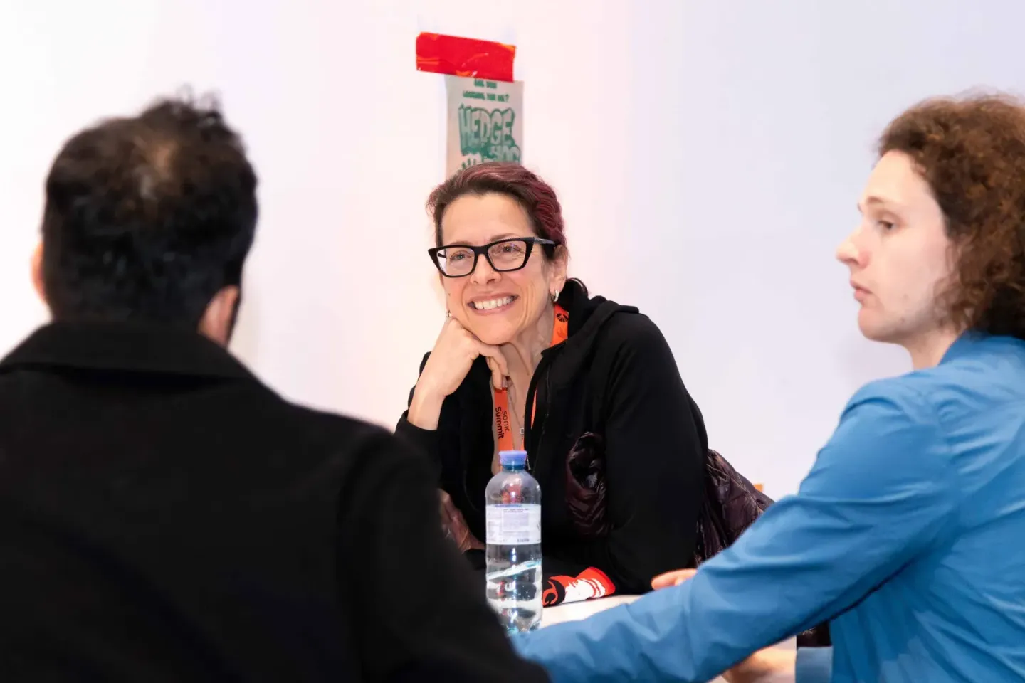 Eventfotograf dokumentiert lebhafte Diskussion zwischen drei Personen beim Sonic Summit in Wien, mit Wasserflasche und Konfer
