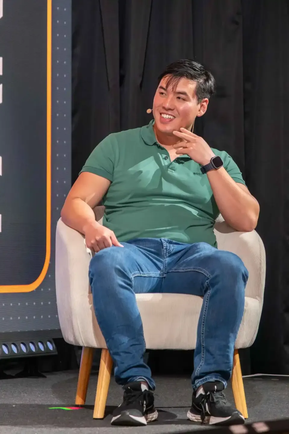 Mann im grünen Polo-Shirt sitzt auf Sessel bei Event-Diskussion, professionelle Eventfotografie Wien