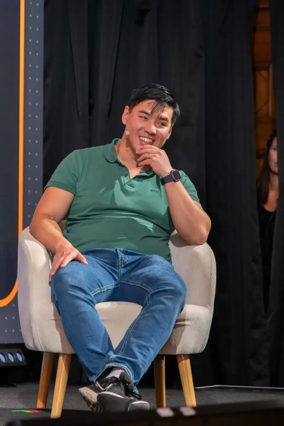 Lachender Mann in grünem Polo-Shirt sitzt auf Sessel bei Eventfotografie Wien Veranstaltung