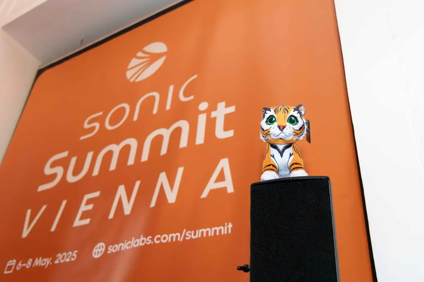 Sonic Summit Vienna 2025 Eventfotografie: Oranges Plakat mit Tiger-Maskottchen auf schwarzem Podium, Veranstaltungsfotograf d