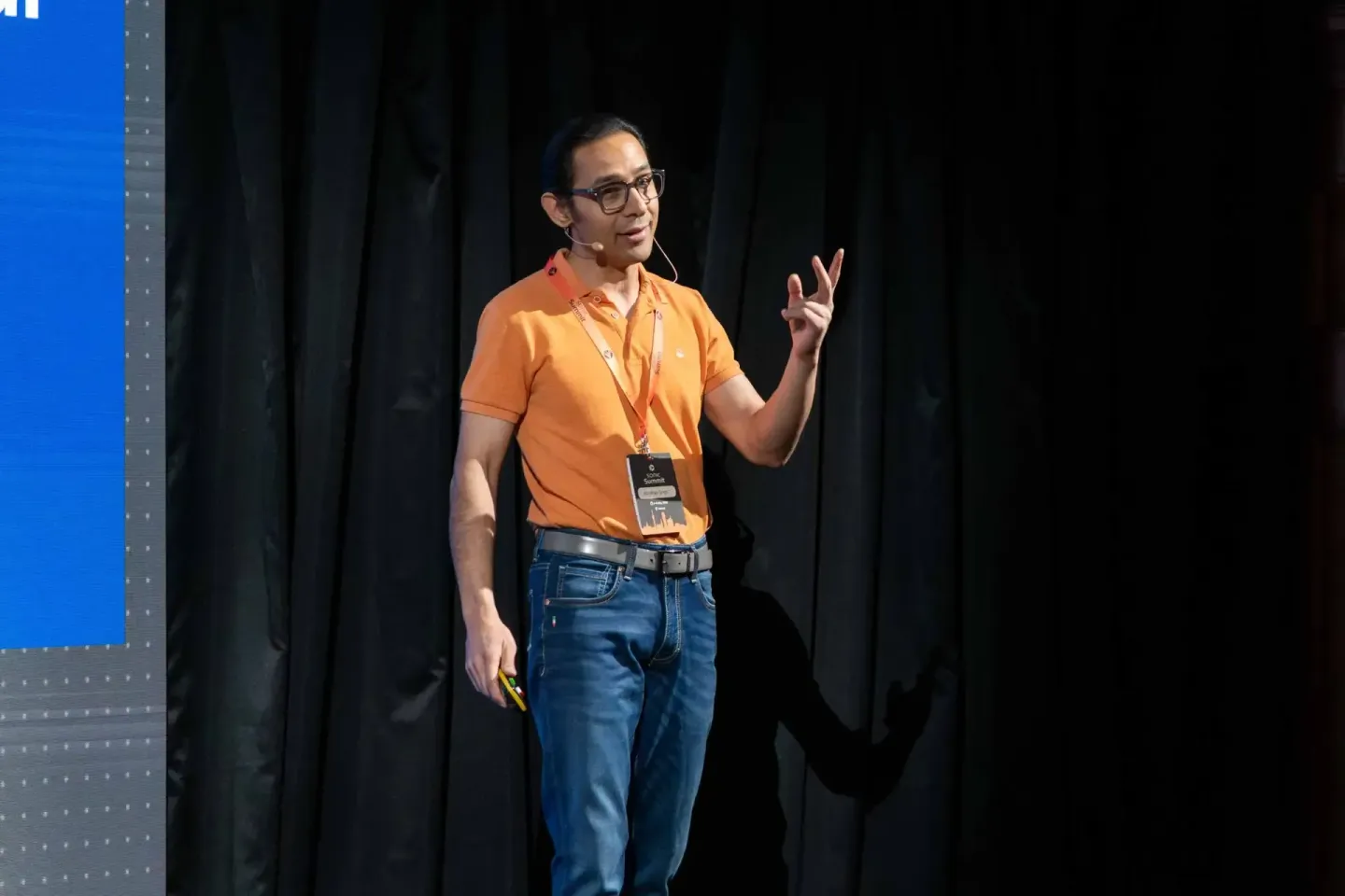 Sprecher in orangem Shirt präsentiert beim Sonic Summit Event vor Publikum - Eventfotografie Wien