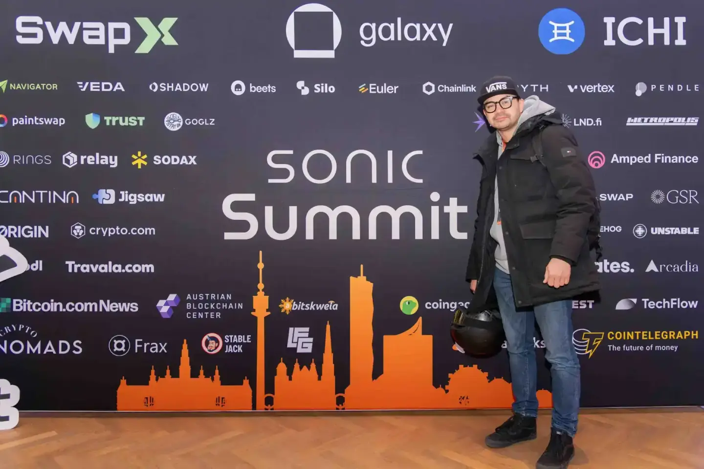 Mann mit Brille und schwarzer Jacke vor Sonic Summit Backdrop mit Wien Skyline, Eventfotografie Wien