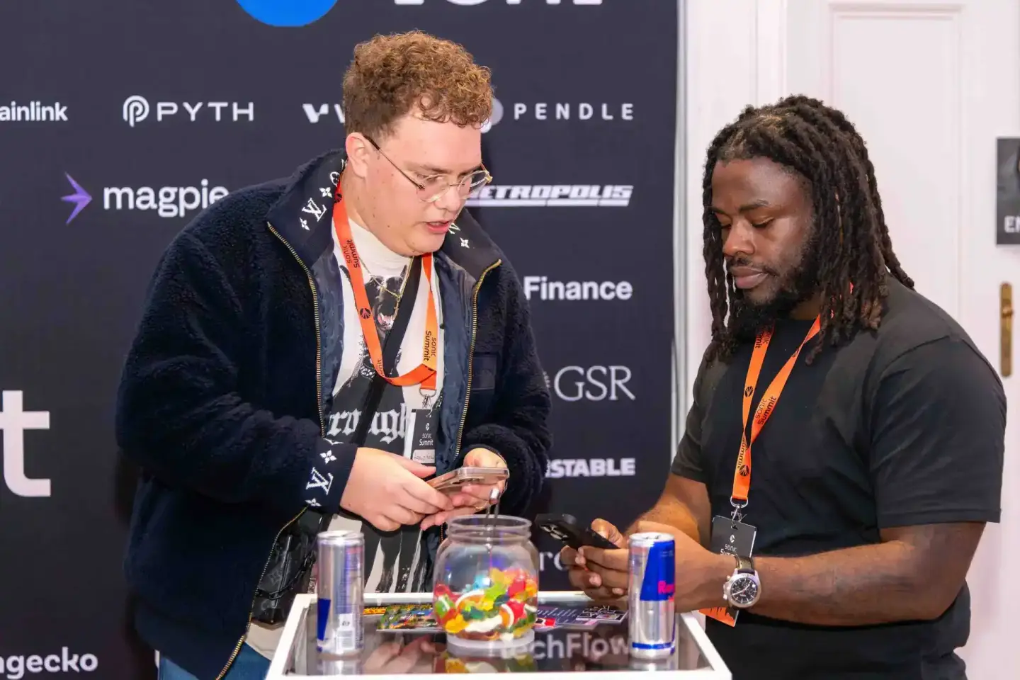 Zwei Teilnehmer beim Sonic Summit Firmenevent Wien tauschen sich an einem Tisch mit Getränken und Süßigkeiten aus