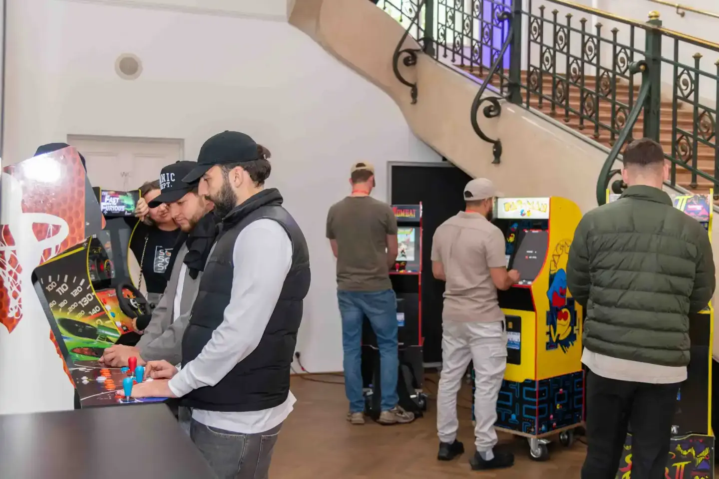 Besucher spielen an Retro-Arcade-Automaten während eines Firmenevents in Wien, Eventfotograf dokumentiert die Szene