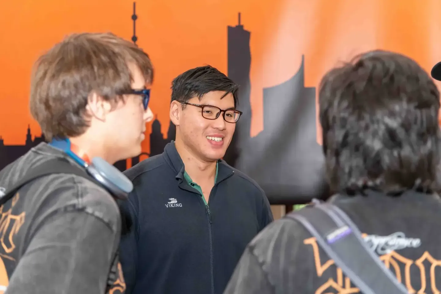 Drei Personen im Gespräch beim Sonic Summit Event, Eventfotograf Wien dokumentiert die Networking-Momente vor Stadt-Skyline H