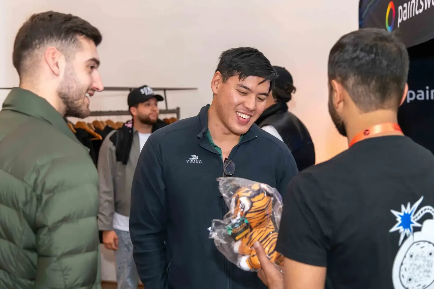 Gäste beim Sonic Summit Event in Wien unterhalten sich angeregt und halten ein Tiger-Plüschtier. Eventfotografie Wien.