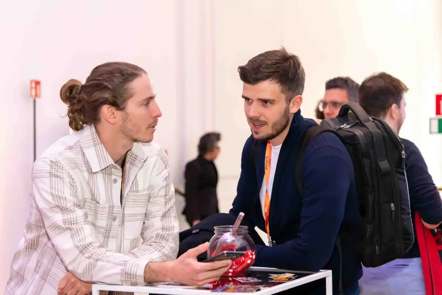 Zwei Männer im Gespräch bei einer Veranstaltung in Wien, einer mit Rucksack und Besucherausweise, Eventfotografie eines profe