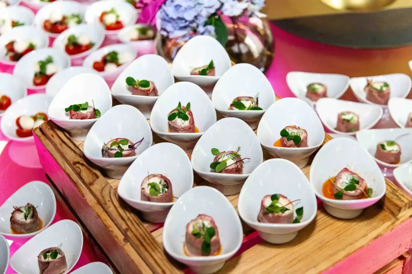 Elegante Appetizer in weißen Schalen auf Holzboard bei einem Wiener Firmenevent – professionelle Eventfotografie