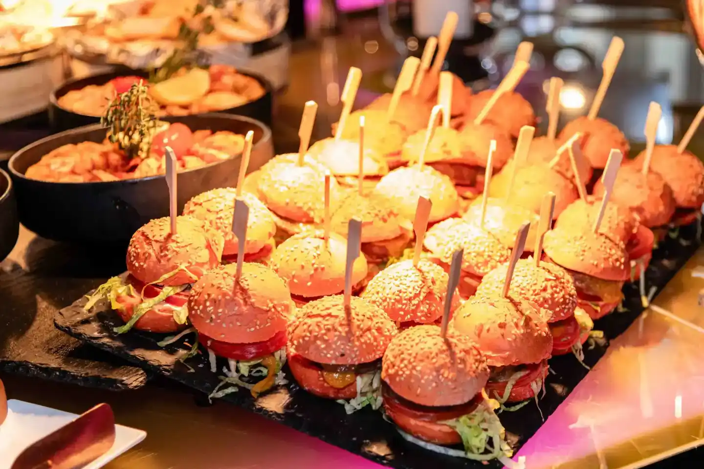 Appetitlich arrangierte Mini-Burger mit Sesam auf schwarzem Slate beim Sonic Summit Event - Eventfotografie Wien
