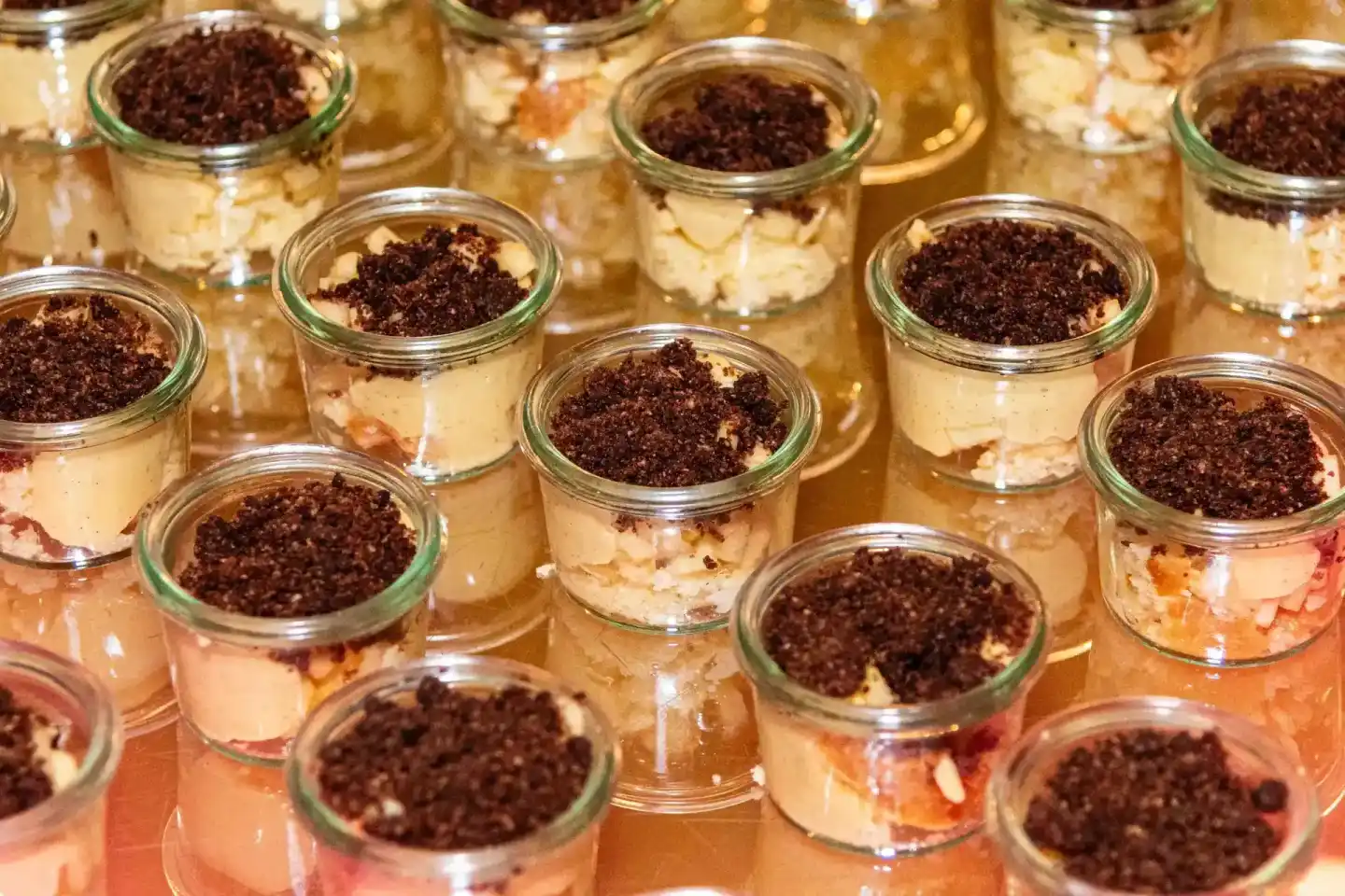 Mehrere Gläser mit Tiramisu-Dessert, garniert mit Kakaopulver, bei einem Firmenevent in Wien