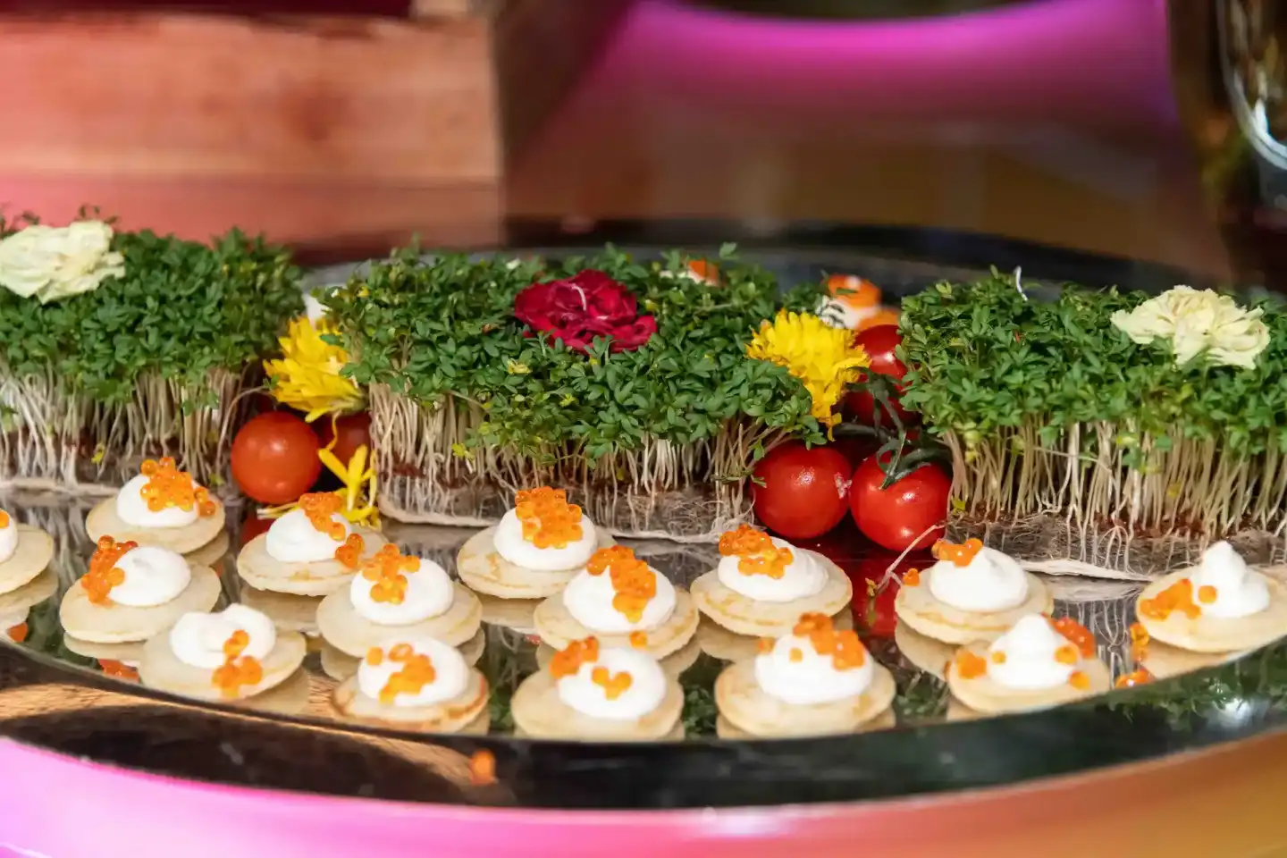 Elegante Catering-Platte mit Kaviar-Häppchen und frischen Blüten bei einem Wiener Firmenevent