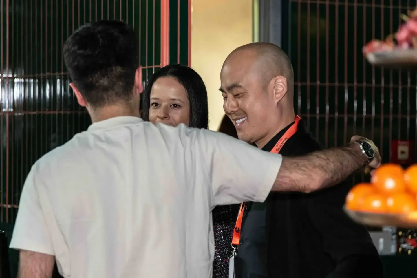 Drei Personen unterhalten sich freundlich auf einem Firmenevent in Wien, zwei tragen rote Lanyards