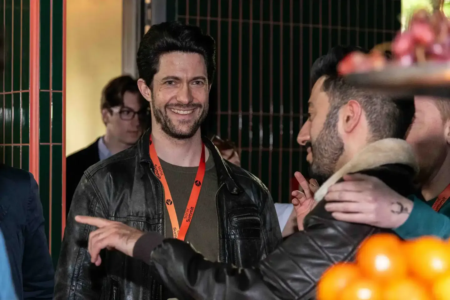 Eventfotograf dokumentiert angeregte Gespräche zwischen Besuchern beim Sonic Summit in Wien, Mann im schwarzen Lederjacket mi