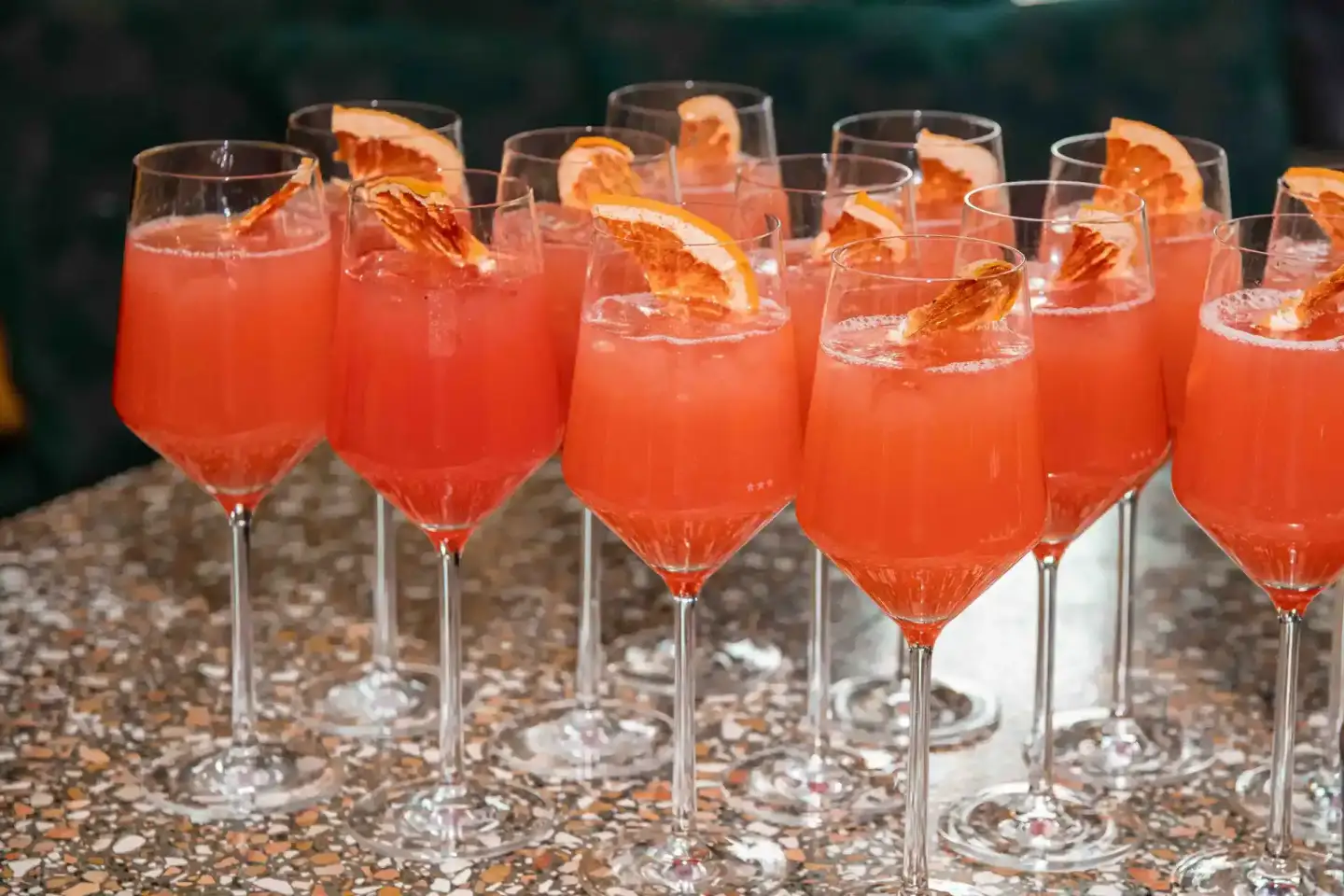 Mehrere Gläser mit orangerotem Cocktail und Grapefruit-Garnierung auf einer Veranstaltung, fotografiert von einem Eventfotogr