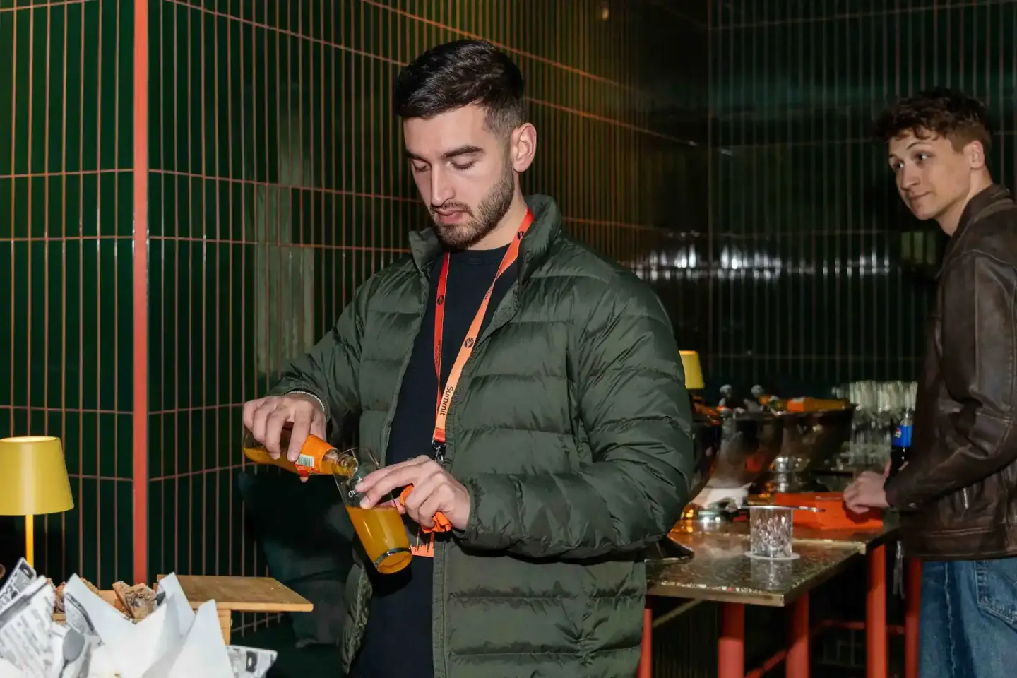 Mann in grüner Daunenjacke öffnet Bierflasche bei Sonic Summit Event, Eventfotograf Wien dokumentiert Veranstaltung