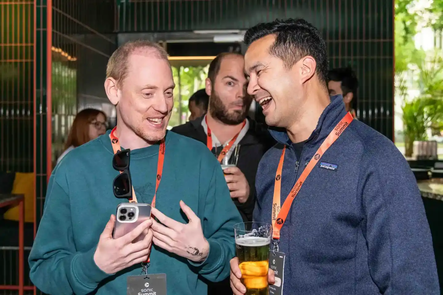 Zwei Männer mit Lanyards lachen beim Sonic Summit Event – professionelle Eventfotografie Wien