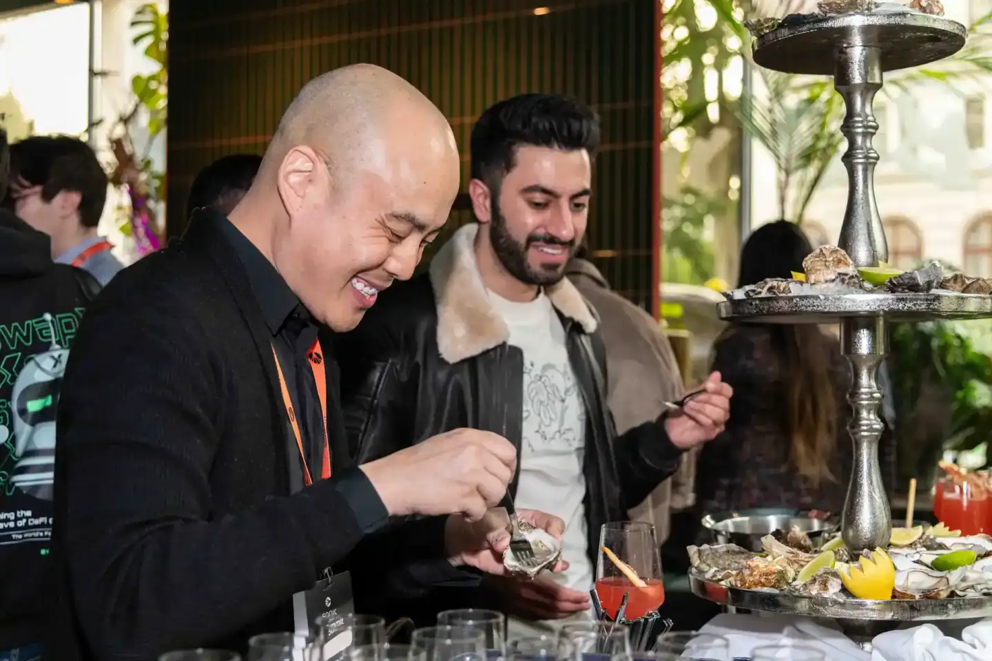 Zwei Männer genießen Oysters bei einem Firmenevent in Wien, im Hintergrund eine elegante Bar mit Pflanzen