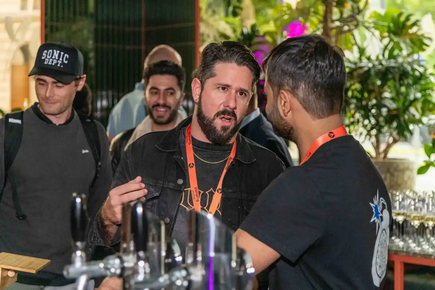 Eventfotograf Wien dokumentiert Networking-Szene beim Sonic Summit mit mehreren Personen im intensiven Gespräch an der Bar