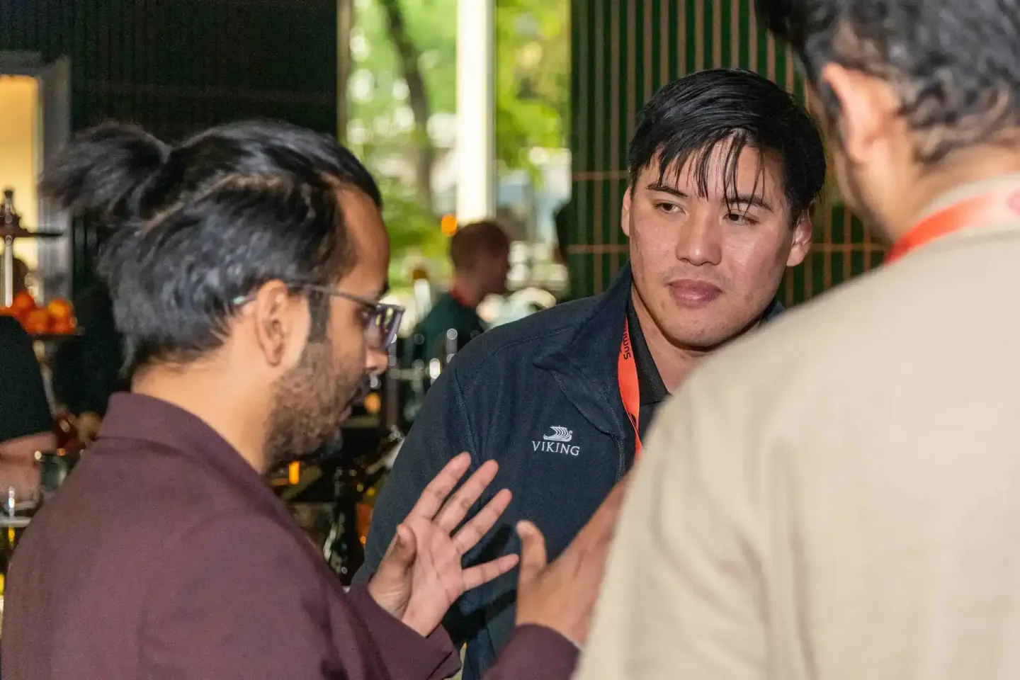 Drei Männer im Gespräch bei einem Firmenevent in Wien, mittlerer Mann trägt Viking-Polo-Shirt