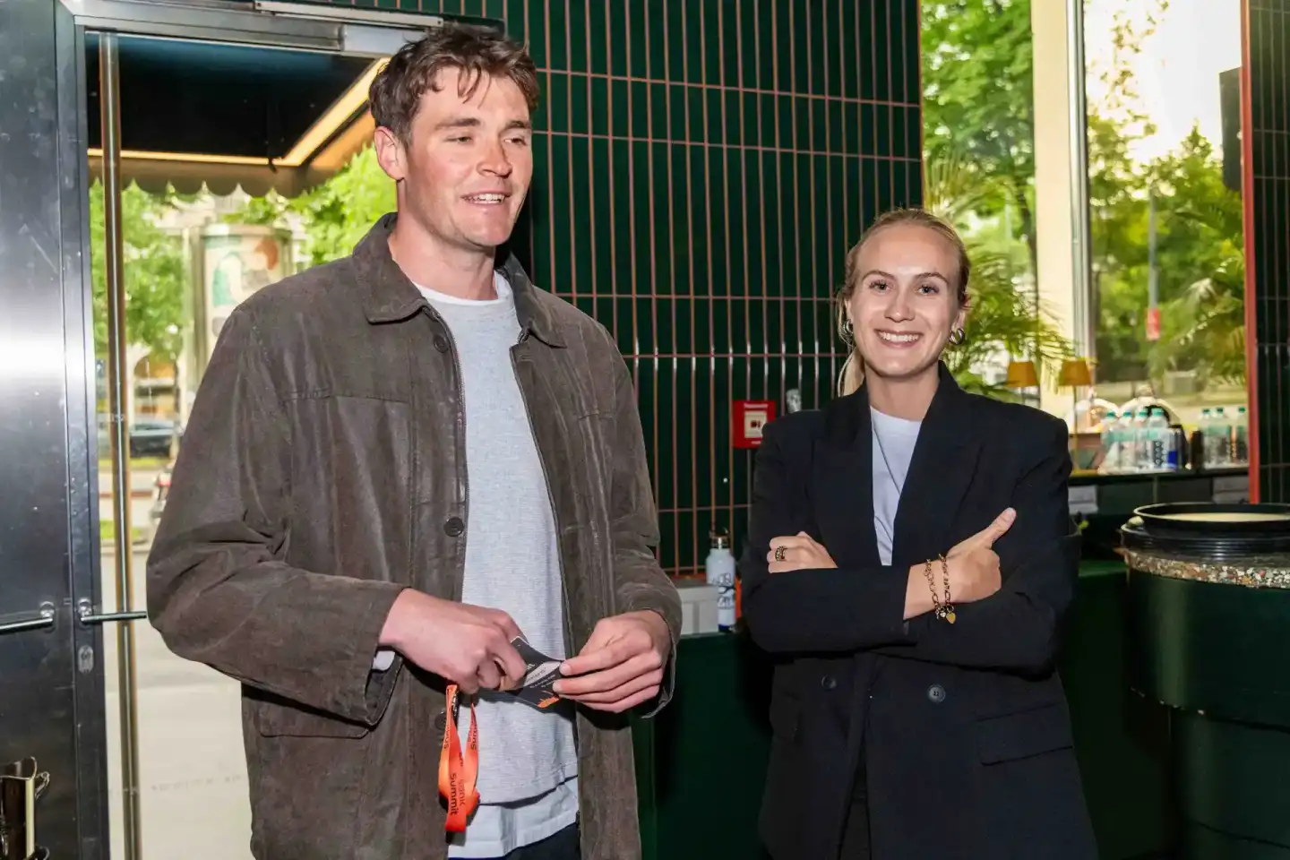 Zwei Personen bei einem Firmenevent Wien, Mann in brauner Jacke und Frau im schwarzen Blazer in angeregtem Gespräch vor grüne