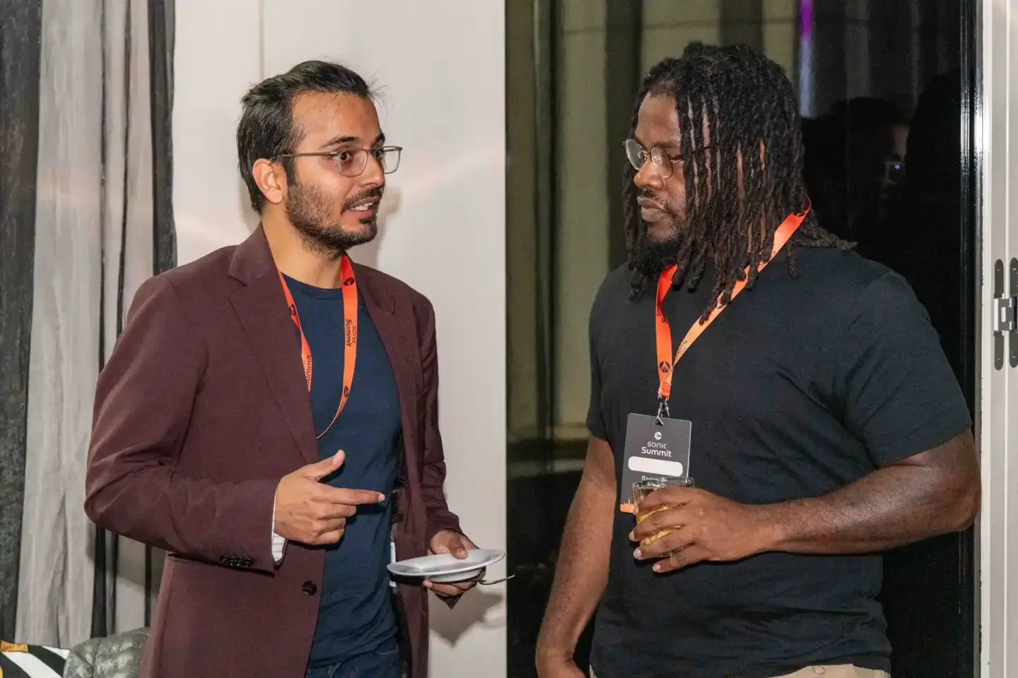 Zwei Männer im Gespräch beim Sonic Summit Event, beide tragen orange Lanyards, Eventfotografie Wien