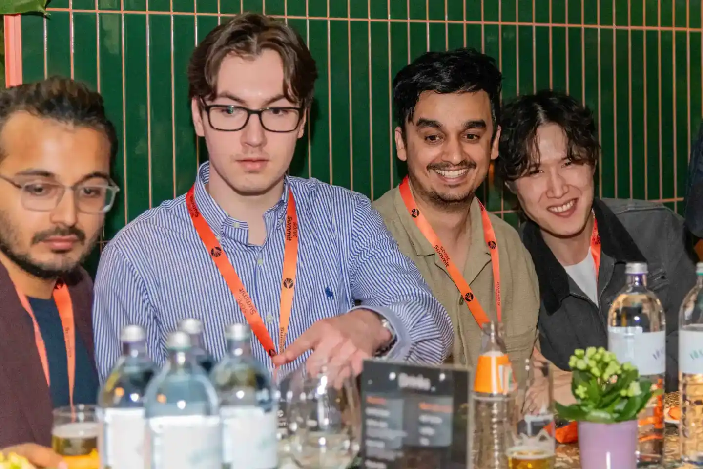 Vier Personen mit orangenen Lanyards sitzen an einem Tisch beim Sonic Summit Event, ein Eventfotograf Wien dokumentiert die K