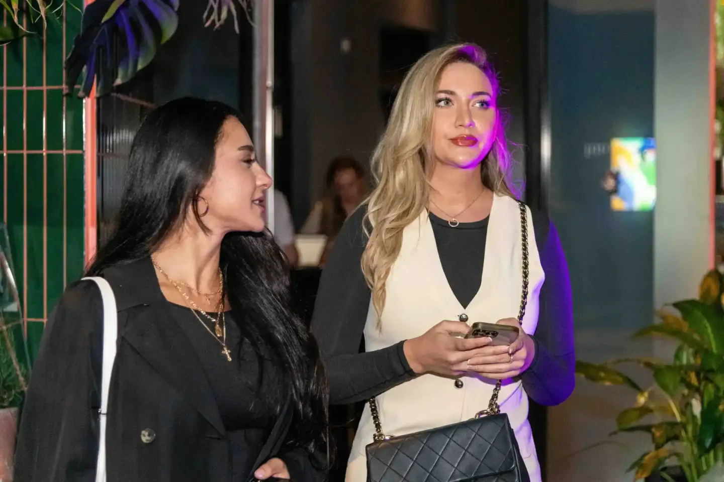 Zwei Frauen in eleganter Abendkleidung unterhalten sich auf einem Firmenevent in Wien mit modernem Ambientelicht