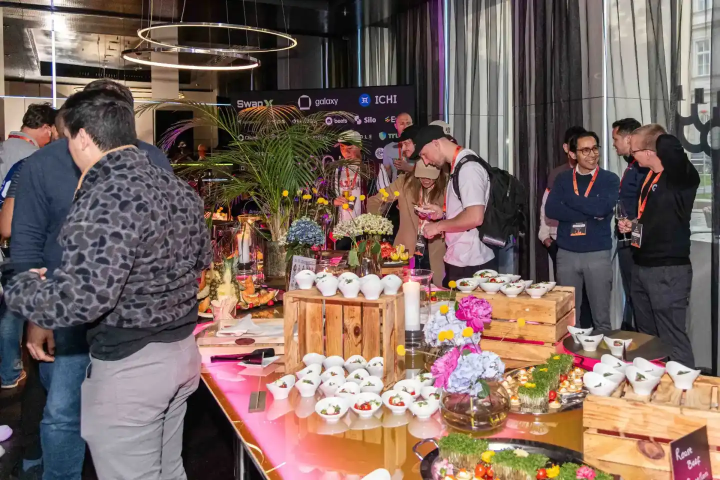 Gäste beim Sonic Summit Event in Wien genießen Catering an liebevoll dekorierten Holztischen mit Blumenarrangements, professi
