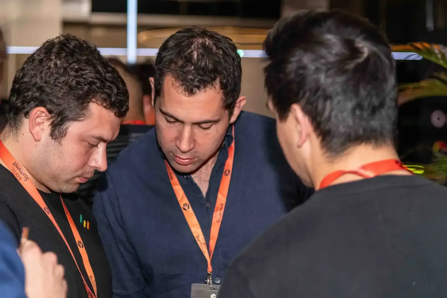 Drei Männer mit orange Lanyards im Gespräch bei einem Event - Eventfotografie Wien