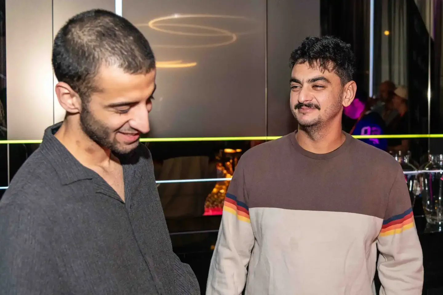 Zwei Männer im Gespräch bei einem Firmenevent in Wien, modernes Event-Setting mit Neon-Beleuchtung im Hintergrund