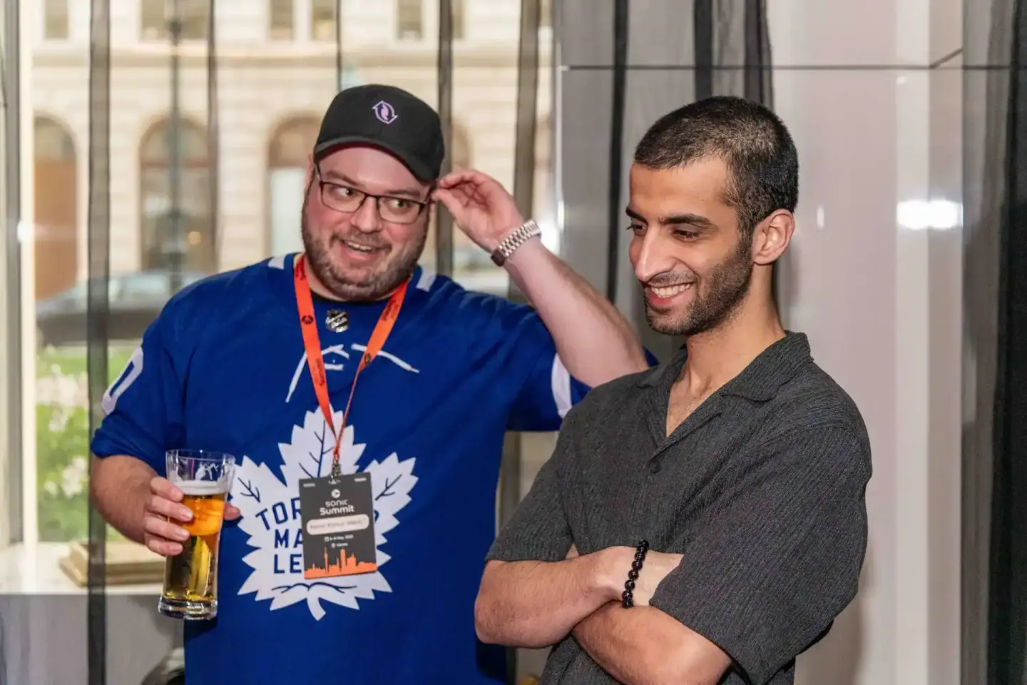 Zwei Männer beim Sonic Summit Event in Wien - einer trägt ein Toronto Maple Leafs Shirt mit Medaille, der andere ein graues H