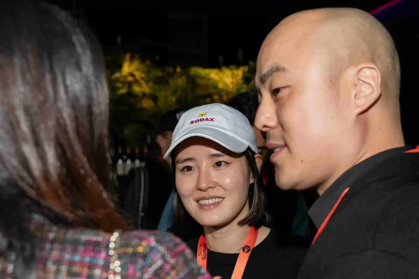 Drei Personen beim Sonic Summit Event in Wien - eine Frau mit SODAX-Cap spricht mit zwei Besuchern während des Firmenevent