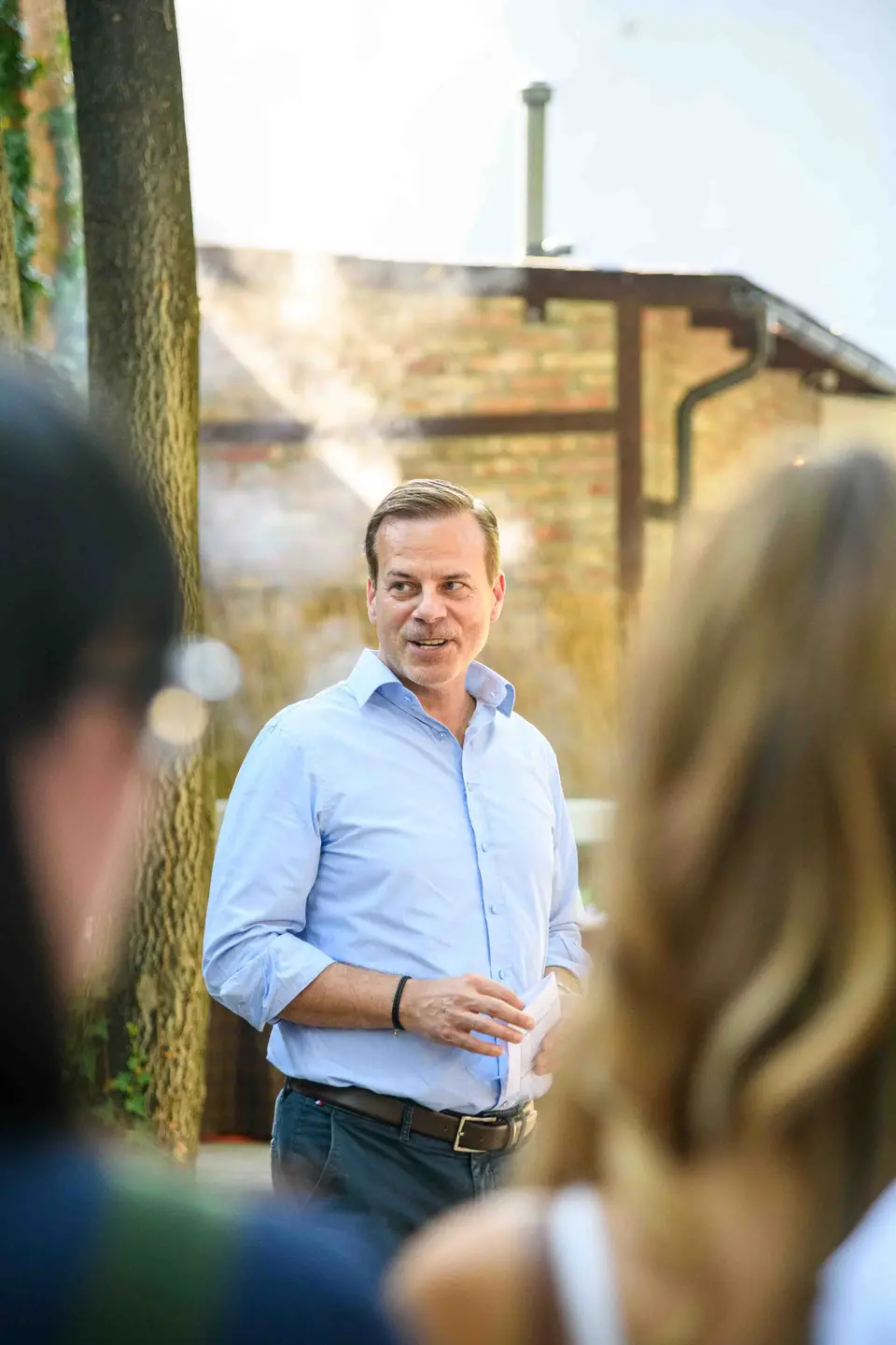 Blick zwischen den Gästen auf den sprechenden Geschäftsführer im blauen Hemd – Sommerfest Wien