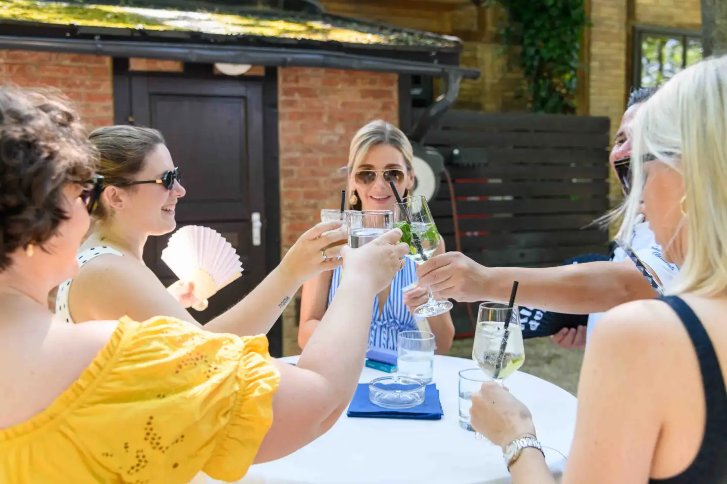 Fünf Kolleginnen stoßen mit Spritzer und Wasser über dem Stehtisch an – Sommerfest Eventfotografie Wien