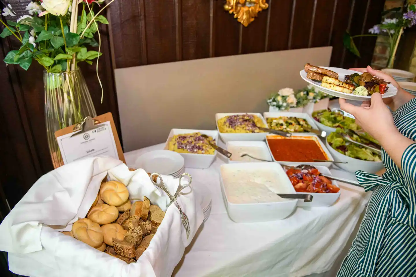 Gast holt sich Gegrilltes am Buffet mit Salaten, Saucen und Gebäckkorb – Firmensommerfest Wien