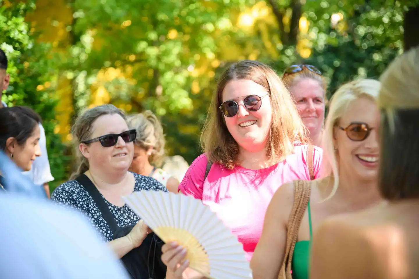 Lachende Gästerunde im Gegenlicht, eine Kollegin im pinken Shirt in der Mitte – Sommerfest Eventfotografie Wien