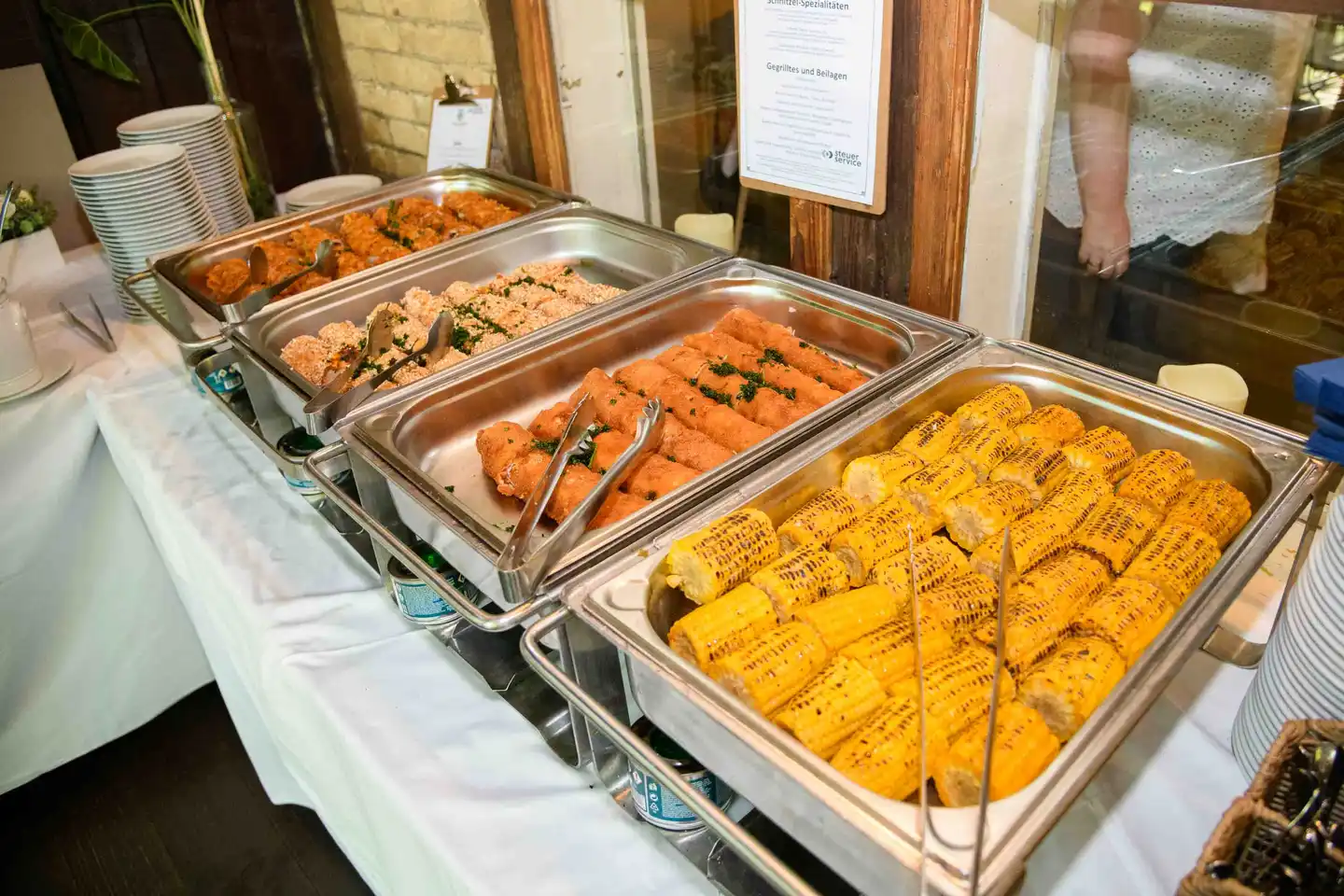 Buffet mit Schnitzelvariationen, Kroketten und gegrillten Maiskolben beim Sommerfest in Wien