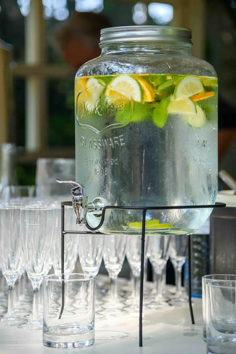 Getränkespender mit Zitronen-Minz-Wasser neben Sektgläsern am Empfangstisch – Sommerfest Eventfotografie Wien