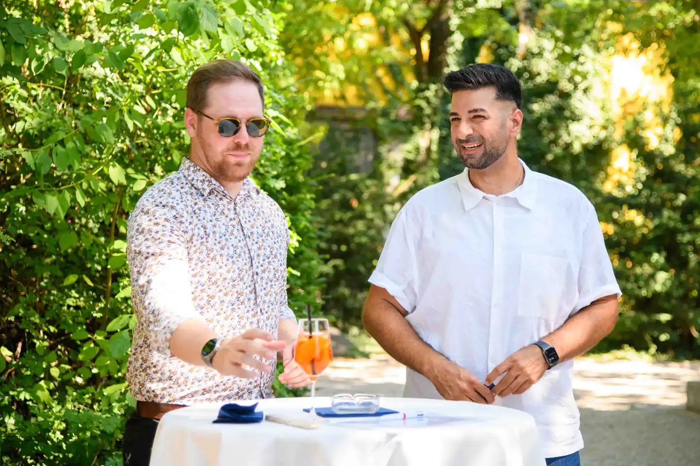Zwei Kollegen am Stehtisch mit Aperol Spritz, einer erzählt lachend – Sommerfest Eventfotografie Wien